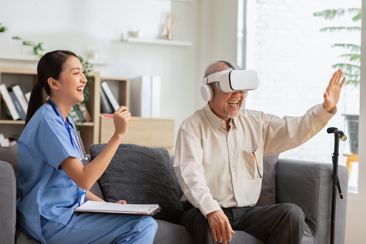 Senior man using VR technology with the assistance of a health care aide.